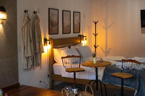 a bedroom with a bed with two chairs and a table at Recanto Águas Nascentes - Chalé Casal com Hidromassagem in Pedra Menina