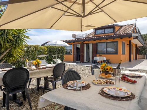 a table with plates of food and an umbrella at Apartment Arancio by Interhome in Zafferana Etnea