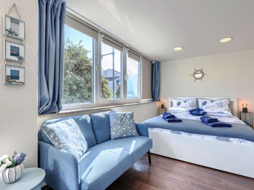 a bedroom with a bed and a couch and windows at Studio Nina by Interhome in Umag