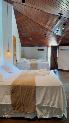 a bedroom with two beds and a wooden ceiling at Pousada Vila Margarida in Chapada dos Guimarães