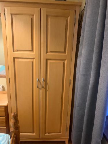 a wooden cabinet with two doors next to a curtain at Kathleen’s Haven in Causeway