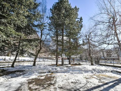a snow covered park with trees and a fence at Apartment Leonardi Terrace by Interhome in Campodolcino