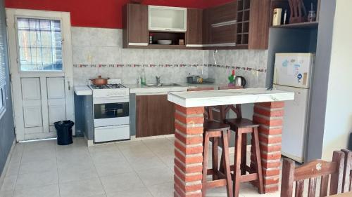 a kitchen with a stove and a counter with stools at La Pasionaria, casa de descanso en villa El Dique in Rosario de Lerma