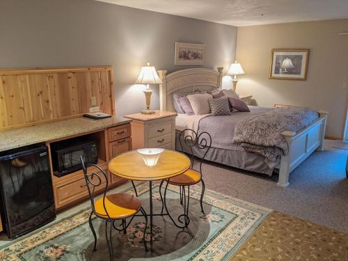 una camera da letto con un letto, un tavolo e delle sedie di Springbrook Inn East Room a Houghton Lake
