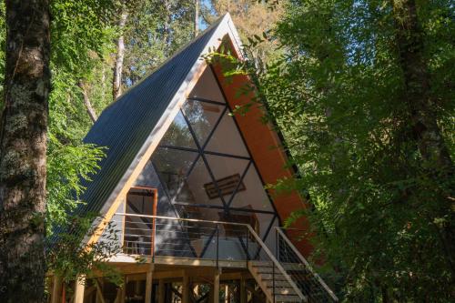 a frame cabin in the woods with a metal roof at Enarbol Lodge, Hot Tube en terraza in Pucón