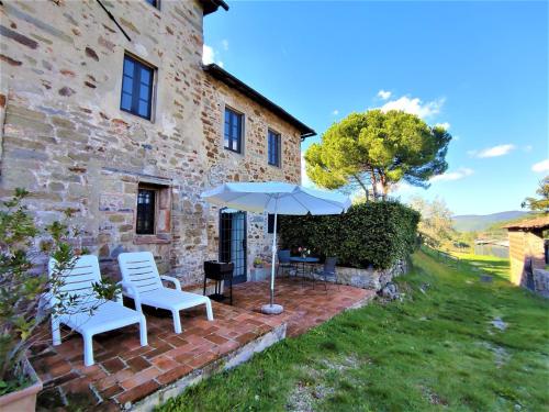 a patio with two chairs and an umbrella in front of a building at Apartment Lavanda by Interhome in Lucolena in Chianti