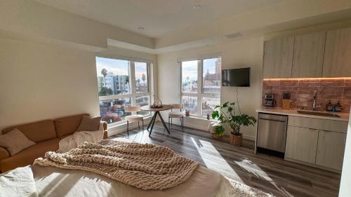 a living room with a couch and a kitchen with windows at Lovely Studio in heart of Hollywood in Los Angeles