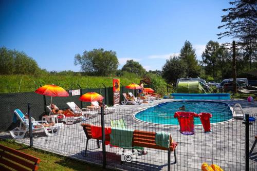 a group of chairs and umbrellas next to a pool at Domki Letniskowe Pod Skamieniałym Miastem in Ciężkowice