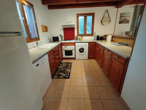 a kitchen with wooden cabinets and a white dishwasher at L'Auzacoise, chalet tout confort pour un séjour inoubliable in Lachapelle-Auzac