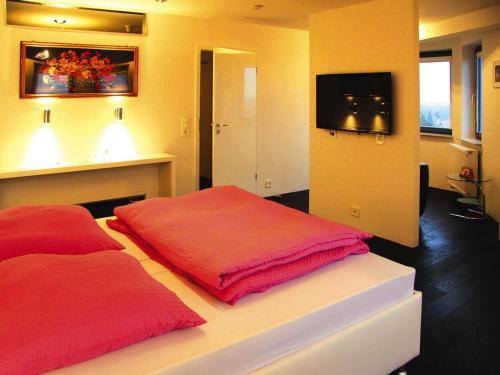 a bedroom with two red pillows and a tv at Ferienwohnung im Wasserturm, Güstrow in Güstrow