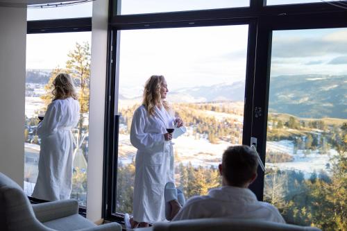 two women in white robes standing in front of a window at Sparkling Hill Resort and Spa - Adults-Only Resort in Vernon