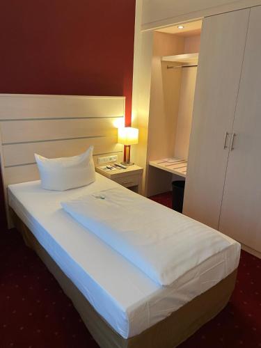 a bedroom with a white bed with a lamp on a table at Aspire AcarA Oldenburg, Trademark Collection by Wyndham in Oldenburg