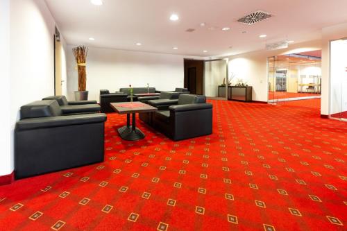 a waiting room with couches and a red carpet at Aspire AcarA Oldenburg, Trademark Collection by Wyndham in Oldenburg