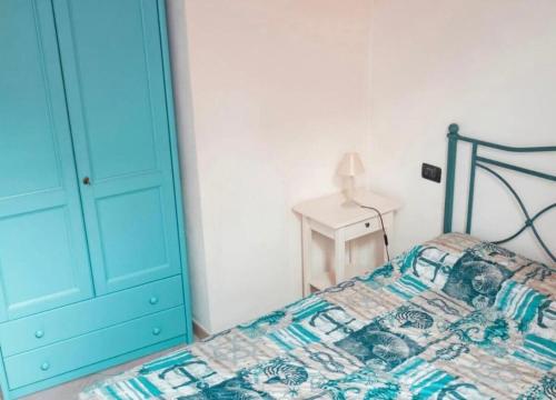 a bedroom with a bed with a blue door and a table at Il Grecale - The Cliff Retreat in Corniglia