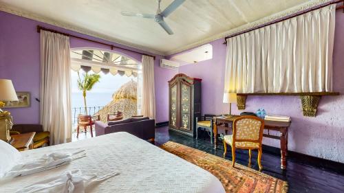 a bedroom with purple walls and a table and a bed at Quinta Maria Cortez Beach Hotel in Puerto Vallarta