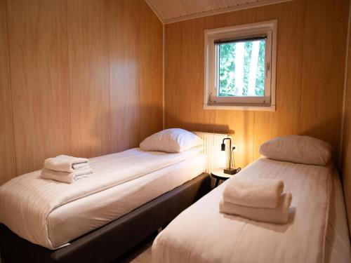 two beds in a small room with a window at Lodge in Brabant with Cozy Covered Terrace in Oirschot