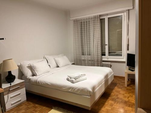 a bedroom with a bed with white sheets and a window at 300m from the train station in Lausanne
