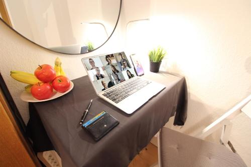 a table with a laptop and a bowl of fruit at Hotel Ulm Zentrum - Komplettes Zimmer, Hochbett, Android TV & eigenem Bad - perfekt für Familien & Gruppen in Ulm