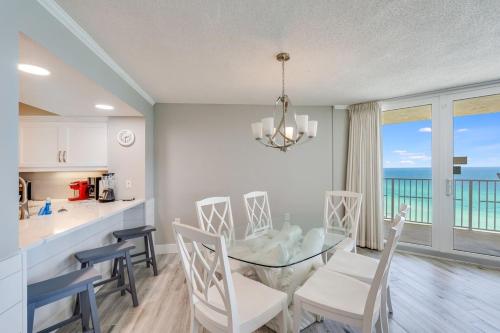 a kitchen and dining room with a glass table and chairs at Dunes of Panama 1506 in Panama City Beach
