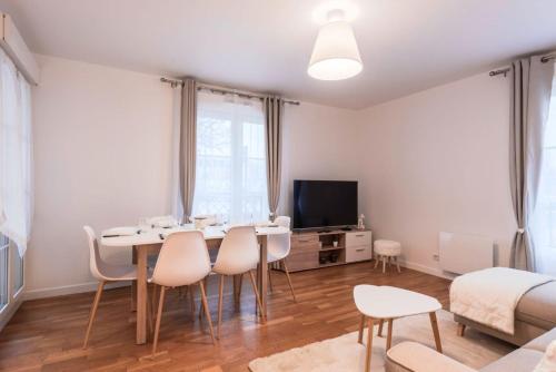 - un salon avec une table, des chaises et une télévision dans l'établissement Villa Saint Honore, à Serris