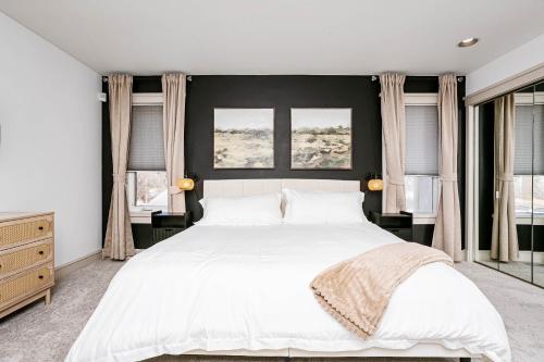 a bedroom with a large white bed with two windows at Chic Central 4BDRM Home-King Bed-AirHockey-Mins DT in Edmonton