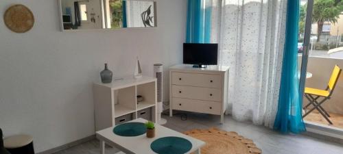 un salon avec une télévision et une table dans l'établissement Très beau Studio Cosy à 500m de la Plage, à Gruissan