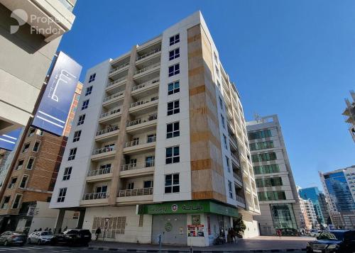 ein hohes weißes Gebäude auf einer Stadtstraße in der Unterkunft Adaz Home in Dubai