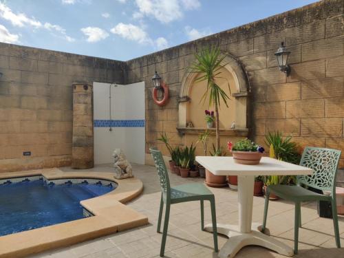 a patio with a table and chairs and a pool at Tan-Namur Farmhouse B&B in Xewkija