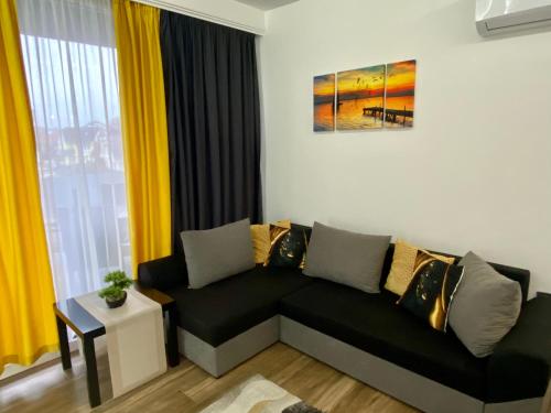 a living room with a black couch and yellow curtains at Pegazus Apartman in Keszthely