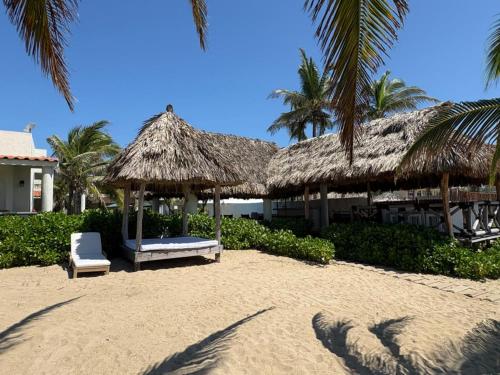 a beach with a straw umbrella and a chair on the sand at Villa Marena Hotel Boutique in Coyuca