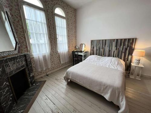 - une chambre avec un lit, une cheminée et des fenêtres dans l'établissement Résidence 006-soulac Sur Mer - 006 - Charmante Villa au cœur de la station MAE-1961, à Soulac-sur-Mer