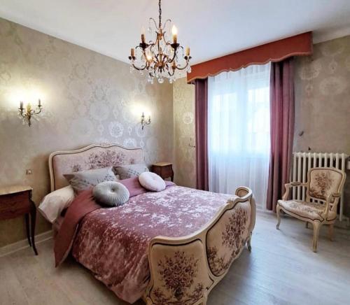 a bedroom with a large bed and a chandelier at La Villa Reina in Le Croisic