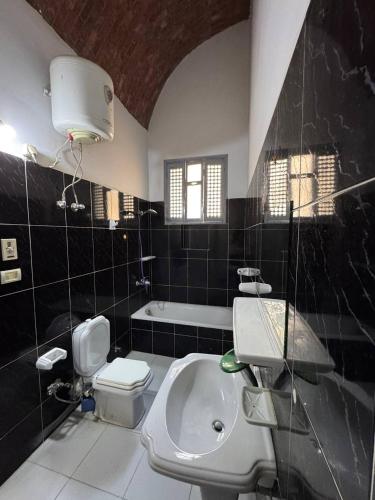 a black and white bathroom with a sink and a toilet at Sahara palace in Luxor