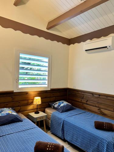 Un dormitorio con dos camas y una ventana. en Baz créole, en Deshaies