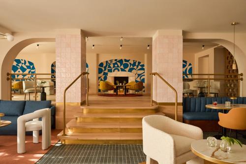 a lobby with a staircase with chairs and tables at Kimpton Los Monteros Marbella by IHG in Marbella