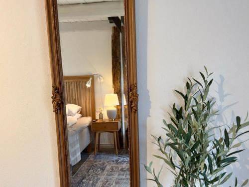 a mirror in a room with a bed and a lamp at Wisteria Österlen in Simrishamn