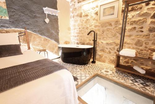 a bathroom with a tub and a bed and a sink at Lo Raconet d'Arnes in Arnés