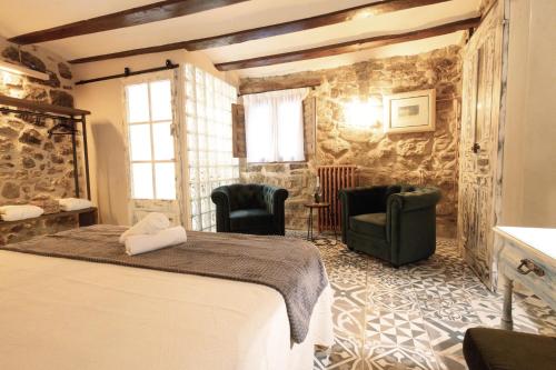 a bedroom with a bed and chairs in a room at Lo Raconet d'Arnes in Arnés