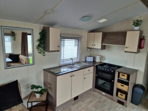 a small kitchen with a stove and a sink at A&J Caravan Hire Golden Gate Towyn in Kinmel Bay