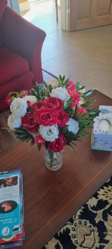 a vase filled with red and white flowers on a table at Doolin Farm Apartment in Doolin