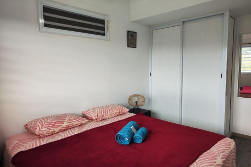 a bedroom with a bed with two blue shoes on it at Neanava Lodge Papeete in Papeete