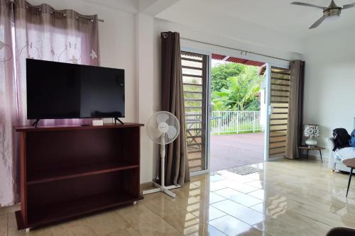 a living room with a flat screen tv on a entertainment center at Neanava Lodge Papeete in Papeete