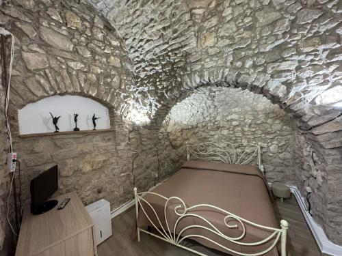 a room with a bed in a stone wall at Casa ''San Giuliani'' - Al Vicolo Case Vacanze in Roccadaspide