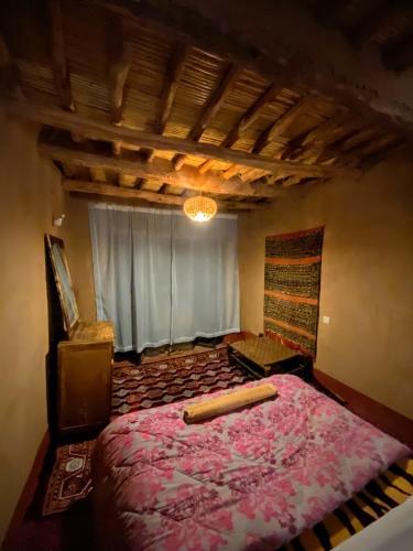 a bedroom with a large bed and a window at Riad La Perle Tamnougalte in Agdz