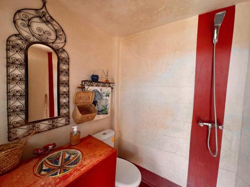a bathroom with a red sink and a mirror at Riad La Perle Tamnougalte in Agdz