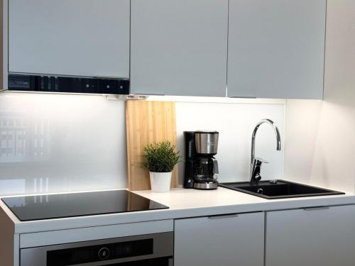 a white kitchen with a sink and a coffee maker at Luxury Apartment With The Best Location In Oulu in Oulu