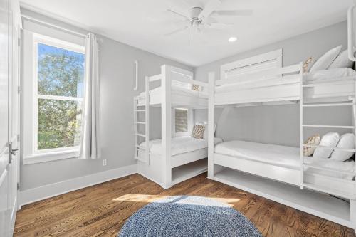 a bedroom with white bunk beds and a window at Sand Pointe by 30A Escapes in Inlet Beach