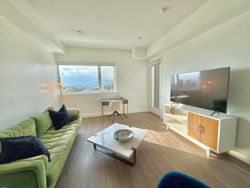 a living room with a green couch and a large television at Top Floor Hollywood 1BR Condo with Views in Los Angeles