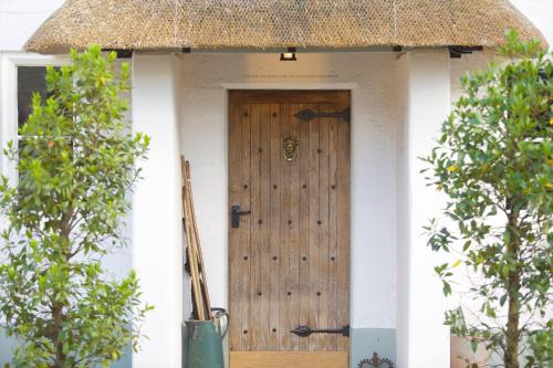 una puerta de madera en una casa blanca con árboles en The Royal Oak, en Anstey