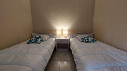 - 2 lits dans une petite chambre avec une table de nuit dans l'établissement Le studio Belle Viste, à Gréoux-les-Bains